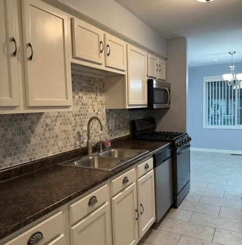 a kitchen with granite countertop a sink stainless steel appliances and cabinets