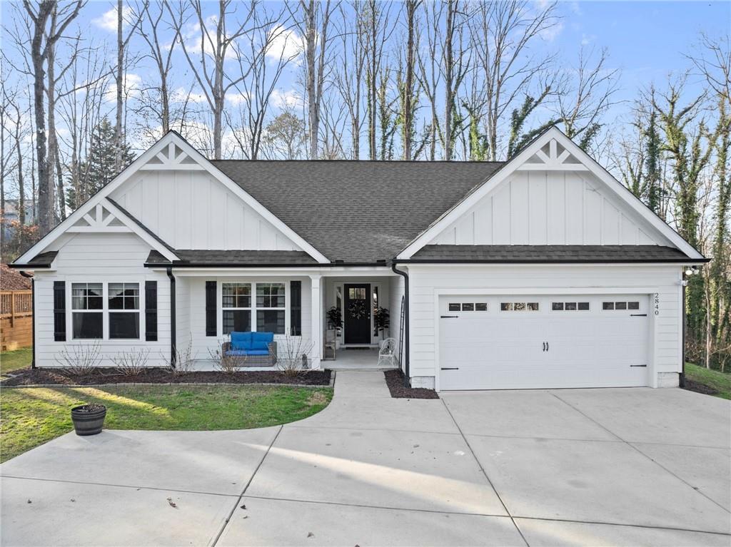a view of a white house with large windows and a yard with plants and large tree