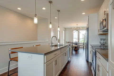 a kitchen with stainless steel appliances a sink dishwasher a stove top oven a refrigerator with wooden cabinets and floor