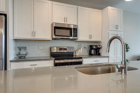 a kitchen with kitchen island white cabinets and stainless steel appliances