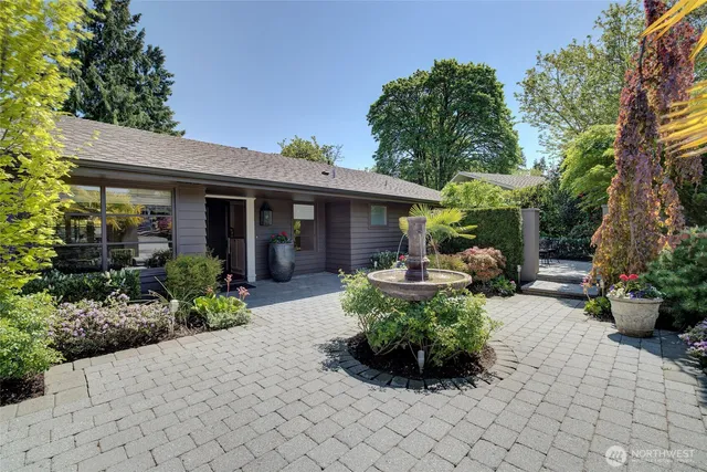 a backyard of a house with table and chairs potted plants and large tree