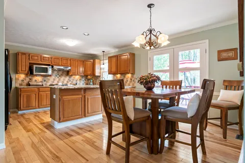 a dining room filled chandelier and wooden furniture