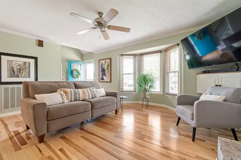 a living room with furniture a ceiling fan a fireplace and a large window