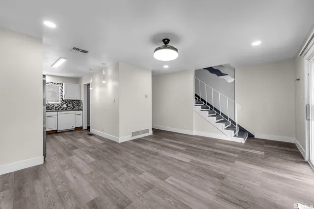 an empty room with wooden floor and a ceiling fan