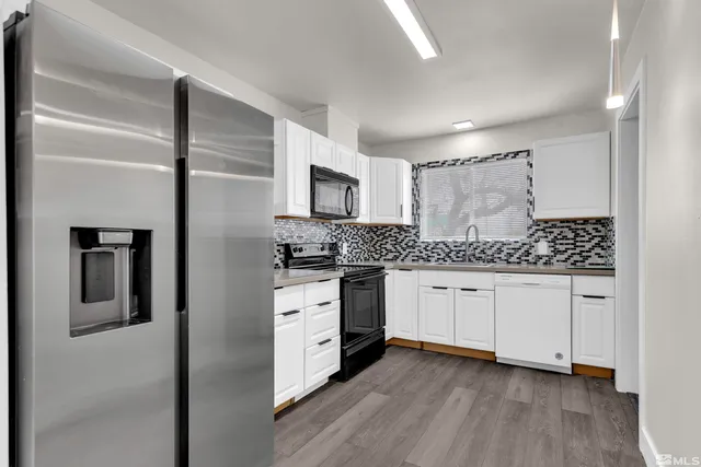 a kitchen with granite countertop white cabinets and stainless steel appliances