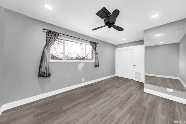 a view of empty room with wooden floor and fan
