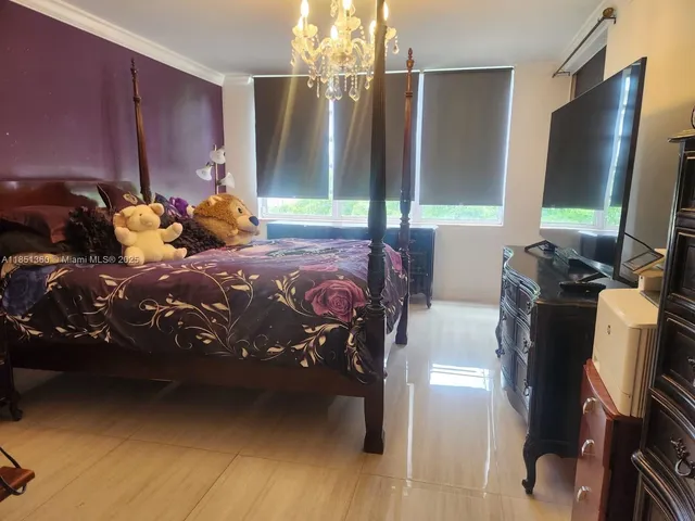 a bedroom with a bed closet and a flat tv screen on dresser