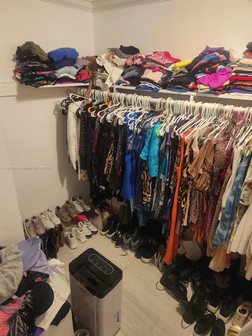 a view of walk in closet with clothes and shoes