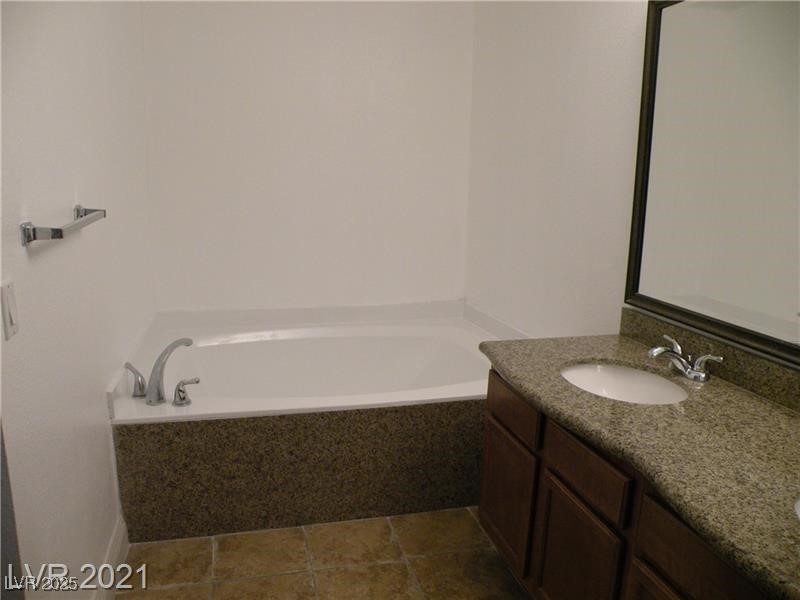 1844 North Decatur Boulevard, Unit 103 Las Vegas, NV 89108 - Photo 6 of 9 Full bath featuring double vanity, a bath, and dark tile patterned flooring