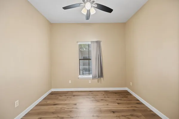 an empty room with wooden floor chandelier and window