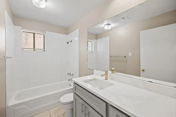 a bathroom with a granite countertop sink a toilet and shower