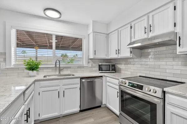 a kitchen with white cabinets appliances and a sink