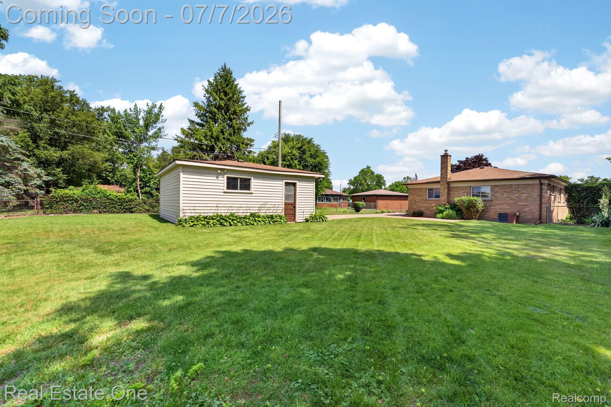 24749 Munson Street Taylor, MI 48180 - Photo 27 of 28 Expansive green lawn with a detached storage shed featuring horizontal siding and a wood-panel door