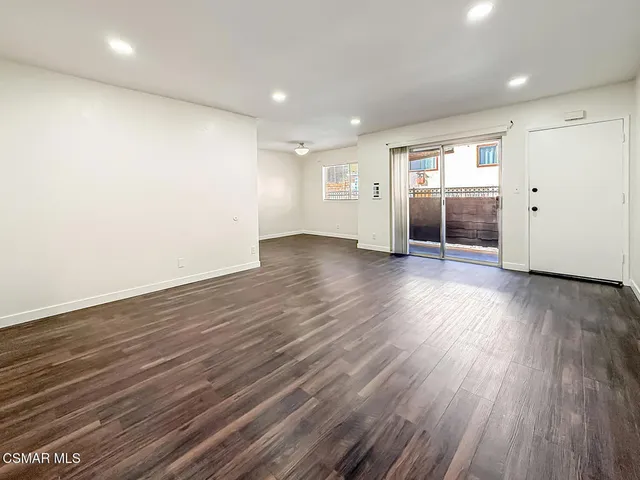 an empty room with wooden floor & windows and ceiling fan