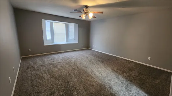 an empty room with windows and chandelier fan