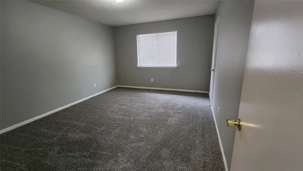 an empty room with a chandelier fan and windows