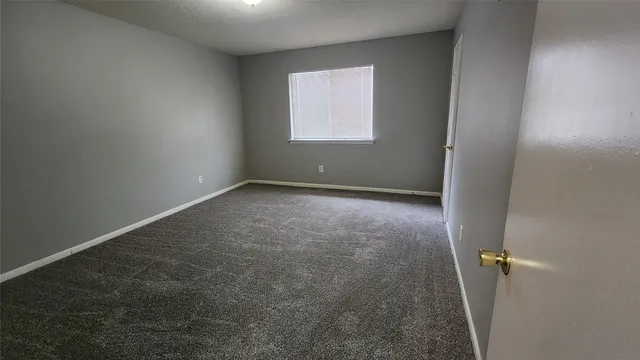 an empty room with a chandelier fan and windows