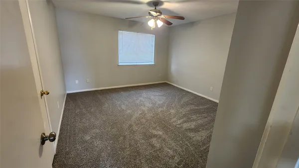 a view of an empty room and chandelier fan