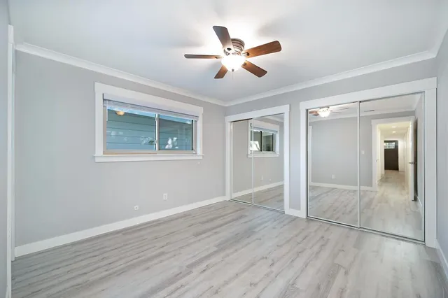 a view of an empty room with wooden floor and a ceiling fan