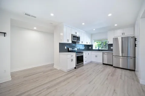 a kitchen with a refrigerator a sink and a stove top oven