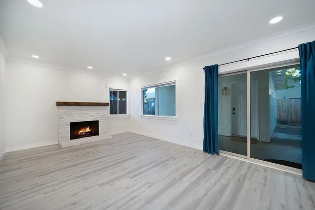 an empty room with wooden floor fireplace and windows