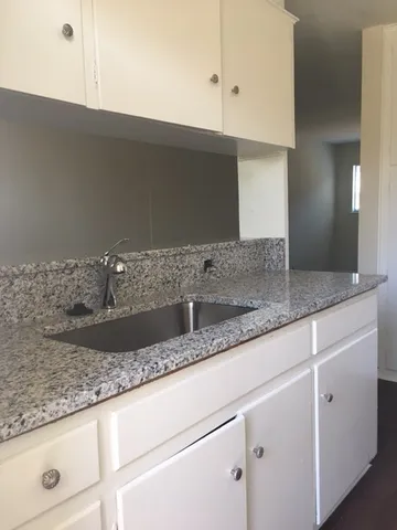 a kitchen with granite countertop a sink and a white cabinets