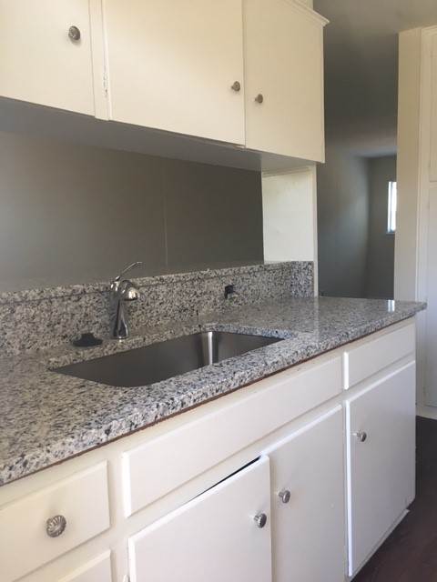 5001 Bull Creek Road, Unit 108 Austin, TX 78731 - Photo 17 of 21 a kitchen with granite countertop a sink and a white cabinets