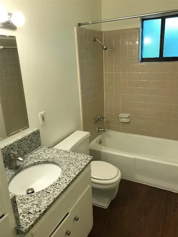 a bathroom with a granite countertop sink a toilet and bathtub