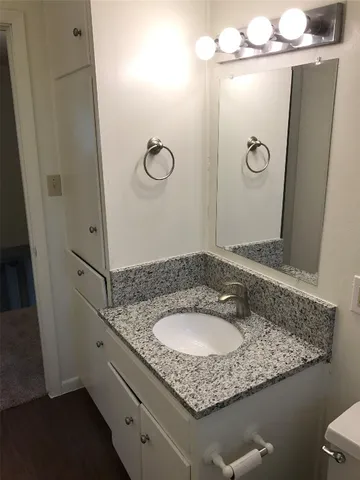a bathroom with a granite countertop sink a mirror and shower