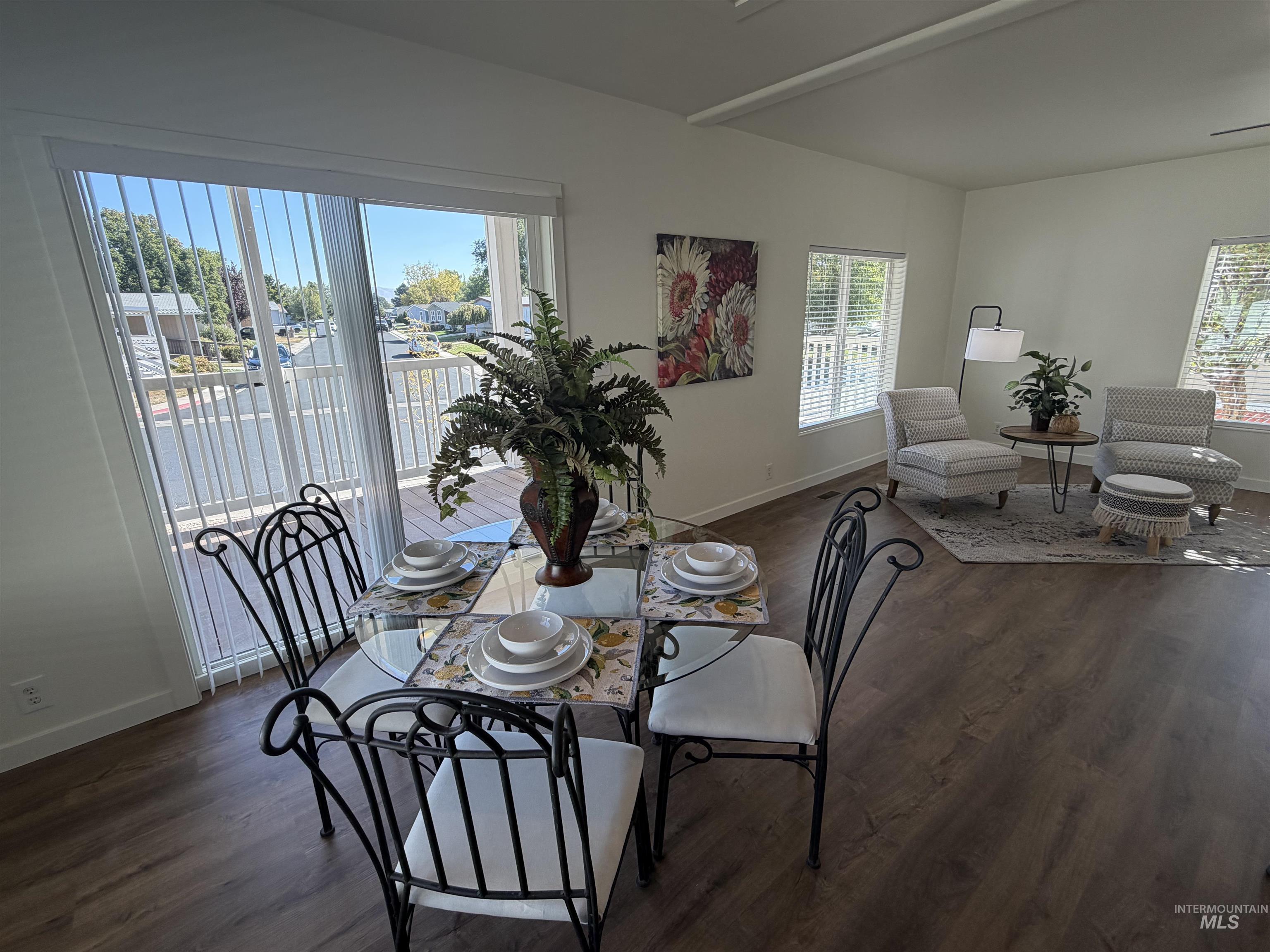 611 North Timathy Road Boise, ID 83713 - Photo 11 of 28 Wood-finish flooring throughout, bright white walls, large windows with blinds, and a sliding glass door leading to an outdoor deck with a railing