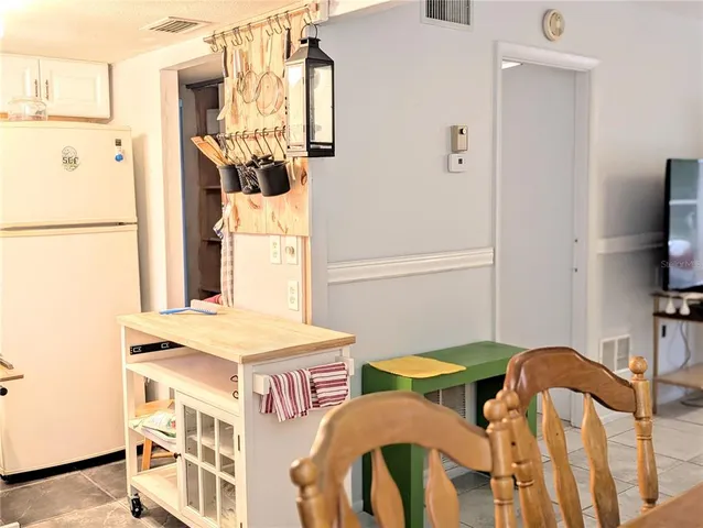 a dining room with furniture a flat screen tv and a refrigerator