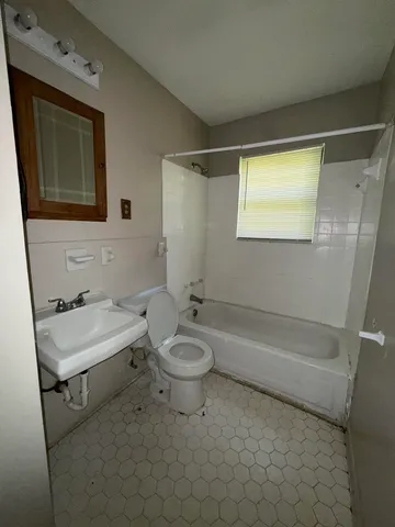 a bathroom with a granite countertop sink toilet a mirror and bathtub