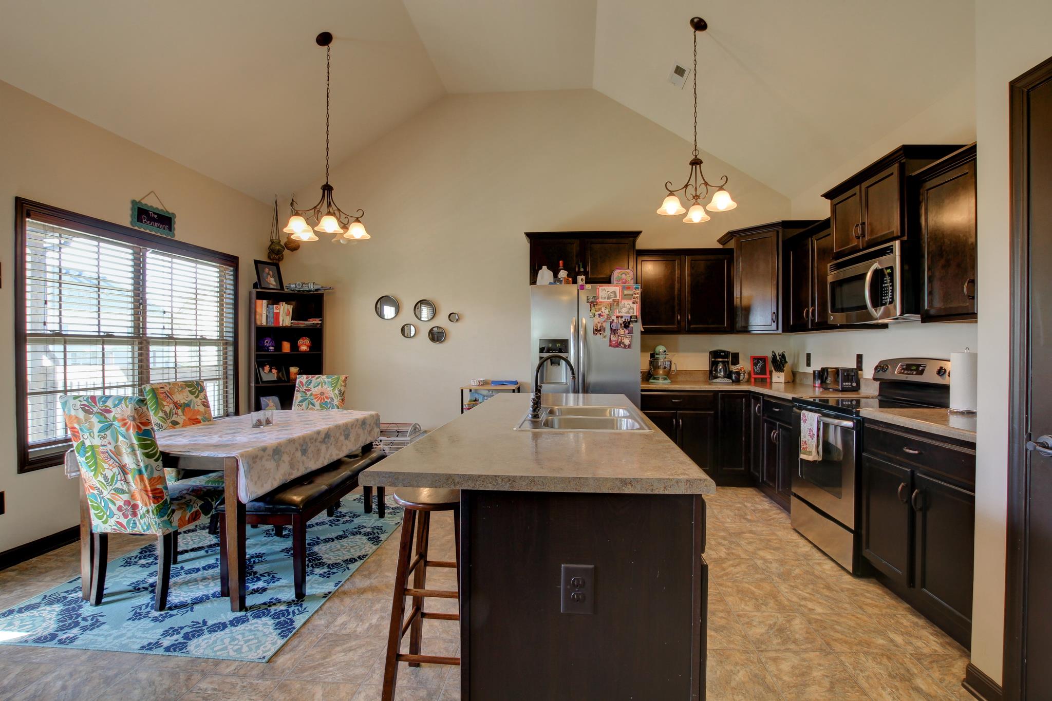 3736 Suiter Road Clarksville, TN 37040 - Photo 6 of 21 a kitchen with stainless steel appliances granite countertop a stove a refrigerator a kitchen island a sink dishwasher a dining table and chairs with wooden floor