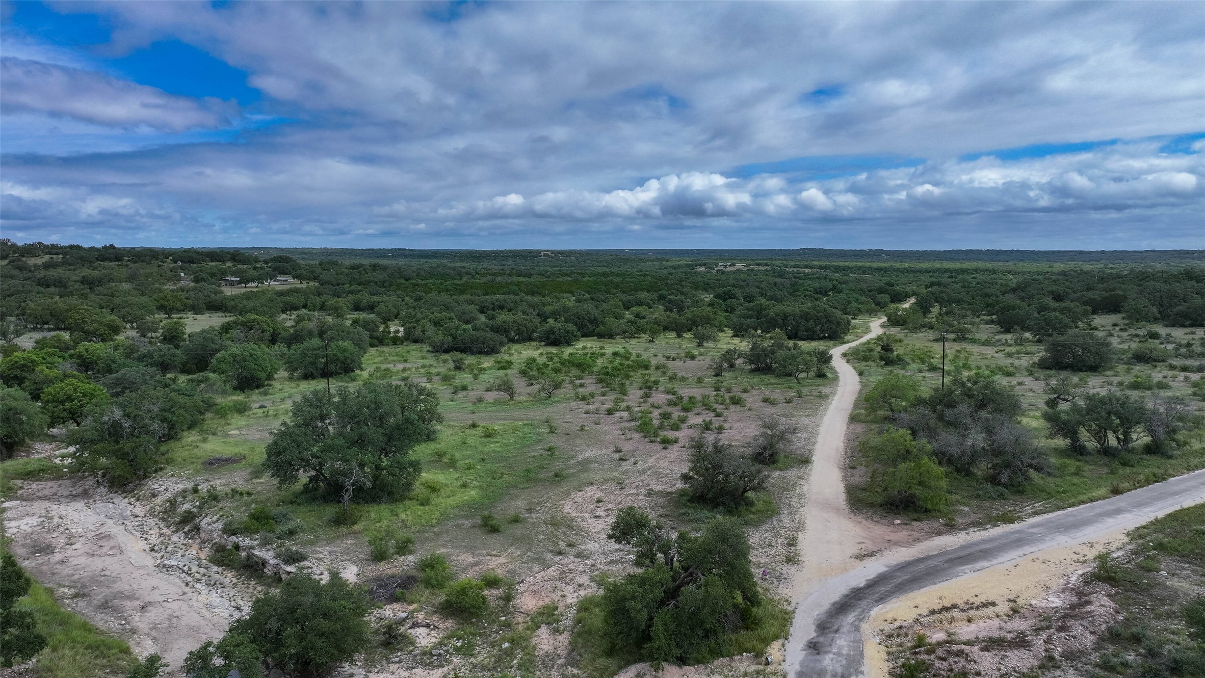 5 Dominion At Oak Ridge Junction, TX 76849 - Photo 15 of 34 Expansive land parcel featuring a gravel road, numerous mature trees, and varied topography