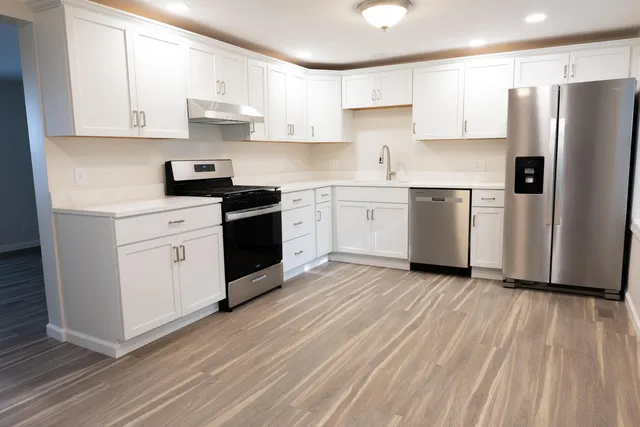 a kitchen with stainless steel appliances white cabinets and a refrigerator