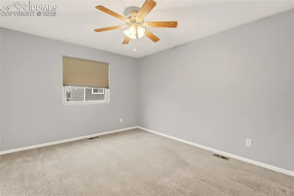 an empty room with a window and a fan