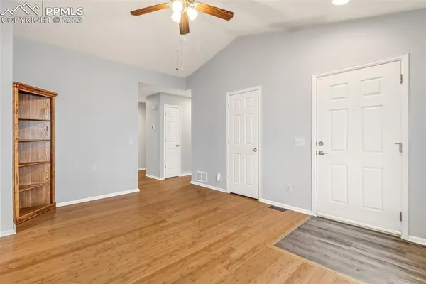 wooden floor in an empty room with a chandelier fan