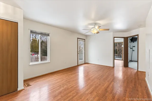 a view of an empty room with window and wooden floor