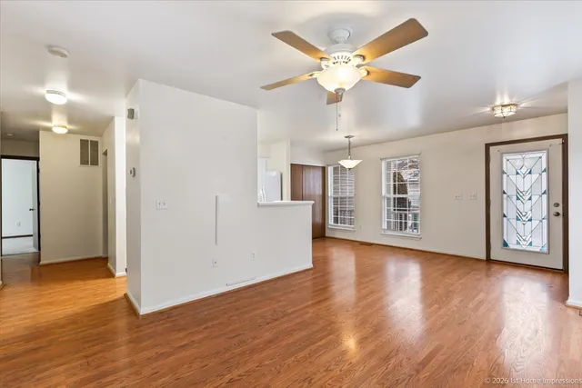 a view of an empty room with window and wooden floor