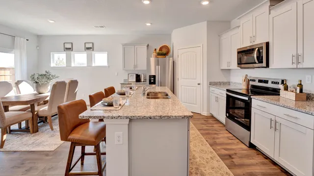 a kitchen with stainless steel appliances kitchen island a table chairs refrigerator sink and cabinets