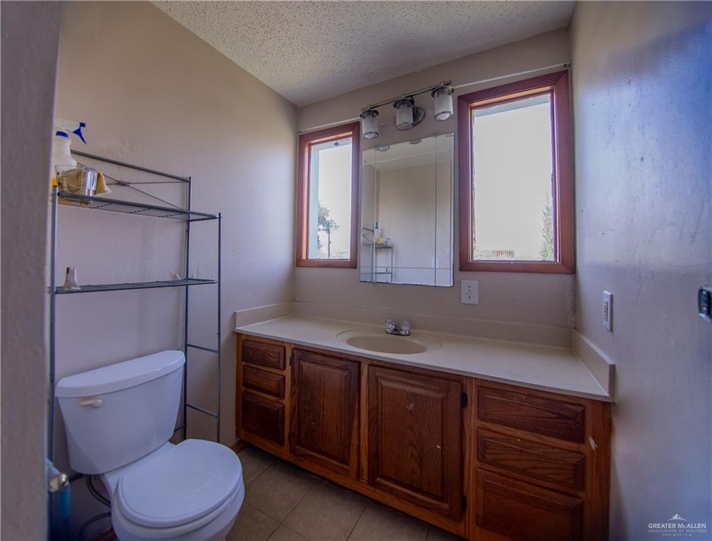 26717 Baker Potts Road Harlingen, TX 78552 - Photo 16 of 18 a bathroom with a toilet sink vanity and mirror