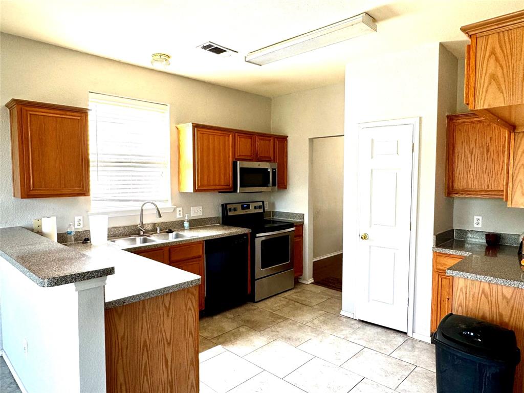 3433 Ingram Road Sachse, TX 75048 - Photo 6 of 23 a kitchen with stainless steel appliances granite countertop a stove a sink a refrigerator and a microwave