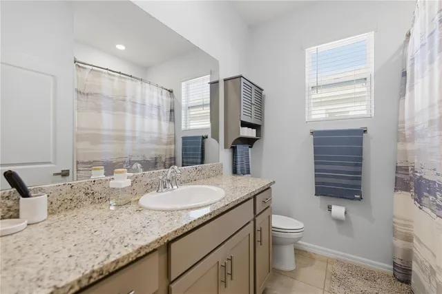 a bathroom with a granite countertop sink toilet and mirror