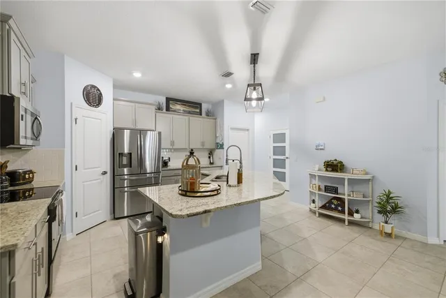 a kitchen with stainless steel appliances kitchen island granite countertop a sink refrigerator and cabinets