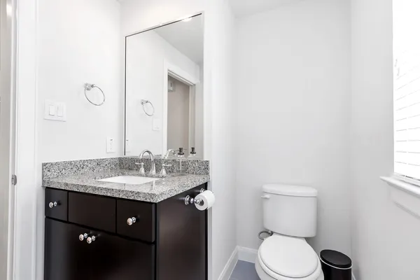 a bathroom with a granite countertop sink toilet and mirror