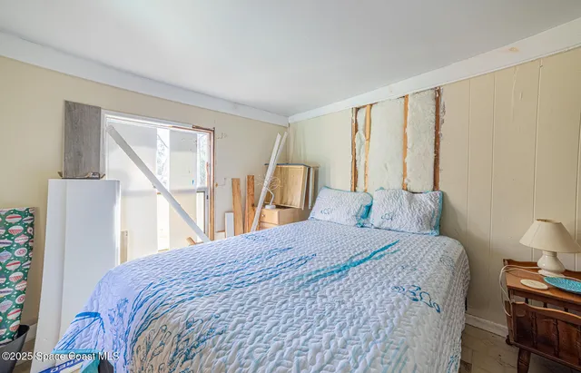 a bedroom with a bed wooden floor and a large window