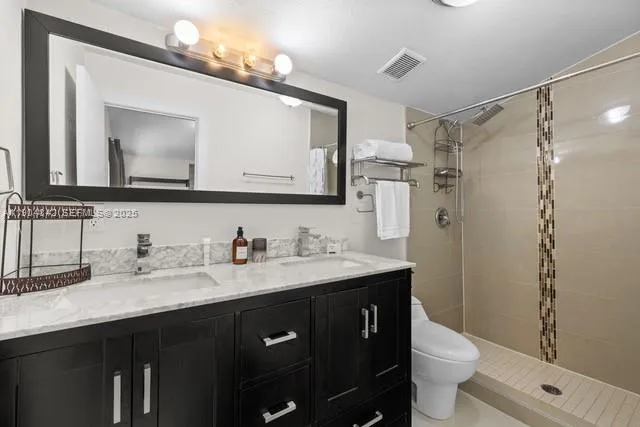 a bathroom with a granite countertop sink toilet a large mirror and shower