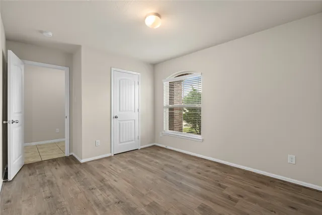 an empty room with wooden floor and windows