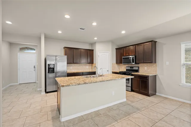 a large kitchen with a large counter top stainless steel appliances and cabinets