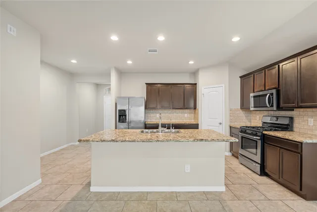 a large kitchen with stainless steel appliances granite countertop a large counter top and a stove top oven with wooden floor